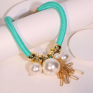 Dettaglio della collana a corda verde con perle finte e ciondoli a spilla di sicurezza oro