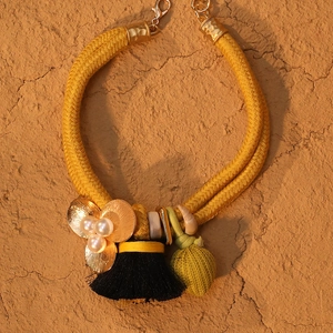 Détail macro d'un collier à franges double couche avec corde jaune et fleur dorée