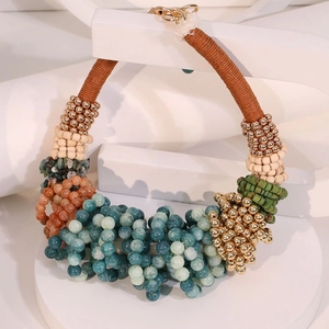 Détail du collier bohème en perles avec cordes tressées et pierres colorées sur socle blanc