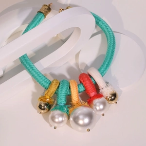 Détail du collier en corde tressée colorée avec perles d'imitation et touches dorées