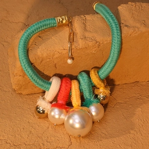Détail du collier tissé bohème avec anneaux multicolores et perles sur fond de sable