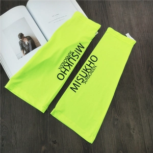 Detail of neon yellow sun protection sleeves with MISUKHO branding on a wooden surface