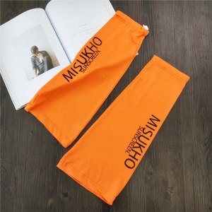 Detail of bright orange sun sleeves with adjustable buckle and letter print on wooden surface