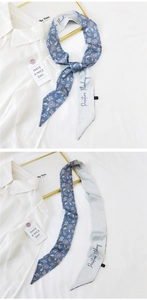 Detail of a double-sided floral and letter print skinny silk scarf tied on a white shirt