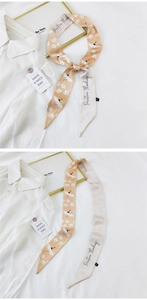 Detail of silk twilly scarf with crane patterns and Positive Thinking text on white fabric