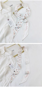 Detail view of a white silk scarf with pink rose prints and Positive Thinking typography