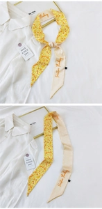 Detail of skinny floral silk scarf with Positive Thinking text tied on a white shirt