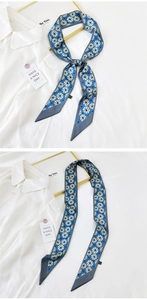 Detail of blue skinny silk scarf with white totem pattern on white shirt background