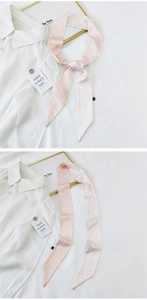 Detailed view of a pink floral skinny silk scarf twilly tied on a white shirt collar