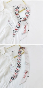 Close-up of narrow silk scarf with red hearts and flowers on white background