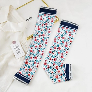 Détail des manchettes de protection solaire à fleurs avec bordure bleue marine