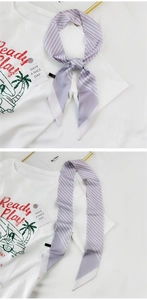 Detail eines lavendelfarbenen gestreiften schmalen Seidenschals an einem T-Shirt