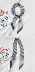 Nahaufnahme eines grau-schwarz gestreiften Seidenschals, gebunden als Modeaccessoire auf Shirt