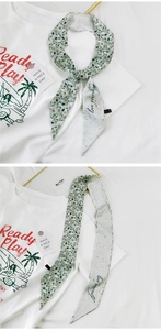 Detail eines Seidenschals mit Love Yourself Aufschrift und beidseitigem Blumenmuster