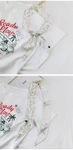 Nahaufnahme cremefarbener schmaler Schal mit Blumenmuster und Love Yourself Text