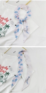 Detail eines rosa floralen Twilly-Schals mit blauen Blumen und Love Yourself Schrift