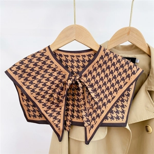 Detail of brown houndstooth decorative fake collar on a trench coat with bow tie