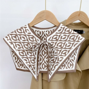 Detail of silk-like shoulder shawl with geometric C-pattern and elegant bow tie closure