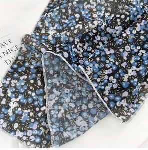 Detailed close-up of light floral linen scarf with fine white overlock stitched edges