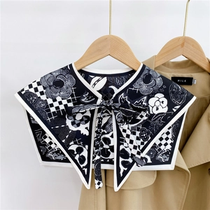 Detail of black and white camellia print shawl wrap tied over a tan trench coat