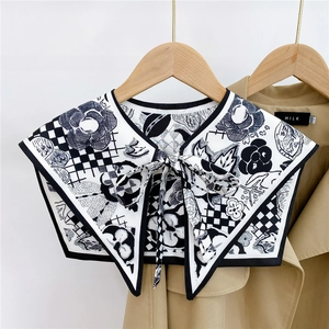 Close-up of decorative black and white floral faux collar shawl with tie-bow on a trench coat