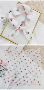 Detail of white chiffon scarf with pink peach print tied in a delicate bow knot