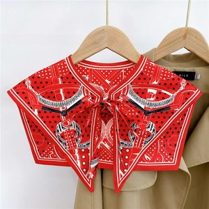 Detail of red printed silk shoulder wrap with equestrian patterns on a khaki trench coat