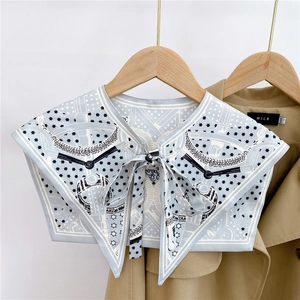 Detail of silk-like shoulder scarf with star patterns knotted over a khaki trench coat