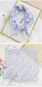 Detail view of light purple silk-like scarf featuring daisy patterns and LOVE lettering