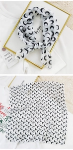 Close-up of white semi-transparent silk scarf with black crescent moon pattern texture