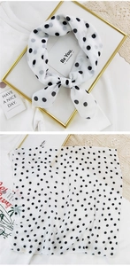 Detail of white semi-transparent polka dot scarf tied in a bow with light chiffon texture