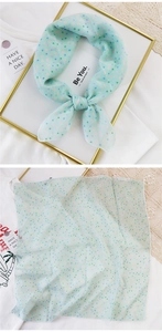 Detail of light green square scarf with colorful dot patterns in a decorative bow layout