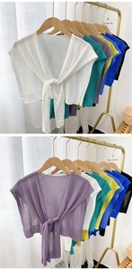 Detail of colorful lightweight knitted shawls tied on minimalist gold clothing racks