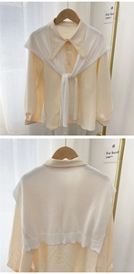 Detail of light yellow lapel shirt paired with a white knitted shawl on a hanger