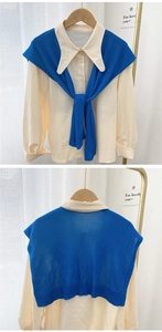 Detail showing beige long-sleeve shirt paired with blue knitted shawl cape scarf