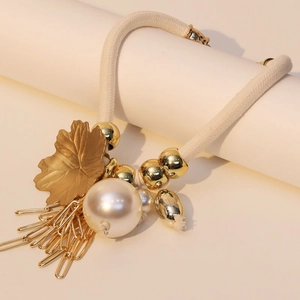Detail of bohemian maple leaf pendant with imitation pearl and gold tassels on rope