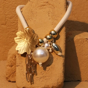 Detail of bohemian leaf necklace with imitation pearl and golden chain tassels