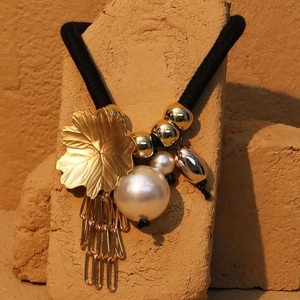 Bohemian maple leaf fringe necklace with faux pearl on rustic stone background
