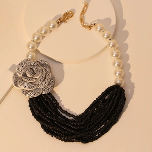 Multi-layer pearl necklace featuring silver roses and black beads on minimalist background