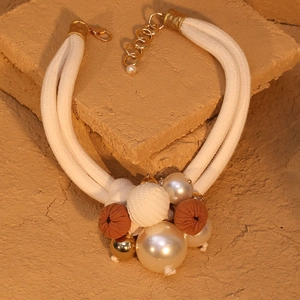 Elegant double-layer rope necklace with pearls and textured fabric charms on stone base