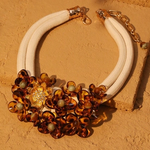 Detail of amber acrylic flower necklace with gold metal base and braided double ropes