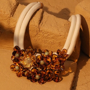 Detail of amber acrylic flower necklace with rhinestones on rustic stone background