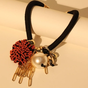 Close-up of red beaded flower and pearl detail on a black woven statement necklace