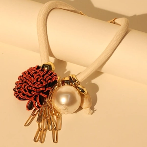 Detailed close-up of crystal flower necklace with pearls and metallic fringe tassels