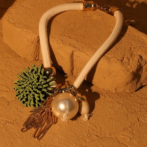 Macro detail of statement floral necklace with large faux pearl and woven rope