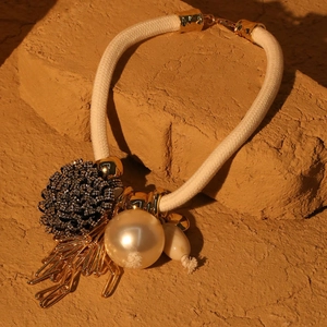 Detailed view of pearl flower necklace with cotton cord, golden tassels and black bead