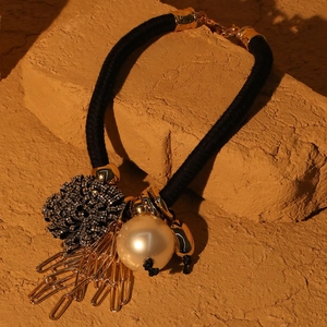 Detail of floral pendant necklace with large faux pearl and golden safety pins on rope