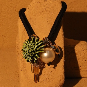 Macro shot of knitted flower hair tie with faux pearl and gold paperclip charms
