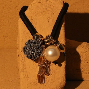 Close-up of hair tie with imitation pearls, rhinestone ball and gold tassel detail