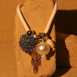Detail of floral necklace with black crystals, large pearl and golden fringe tassels